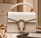 white Gucci Dionysus top handle bag with a silver-tone tiger head closure.